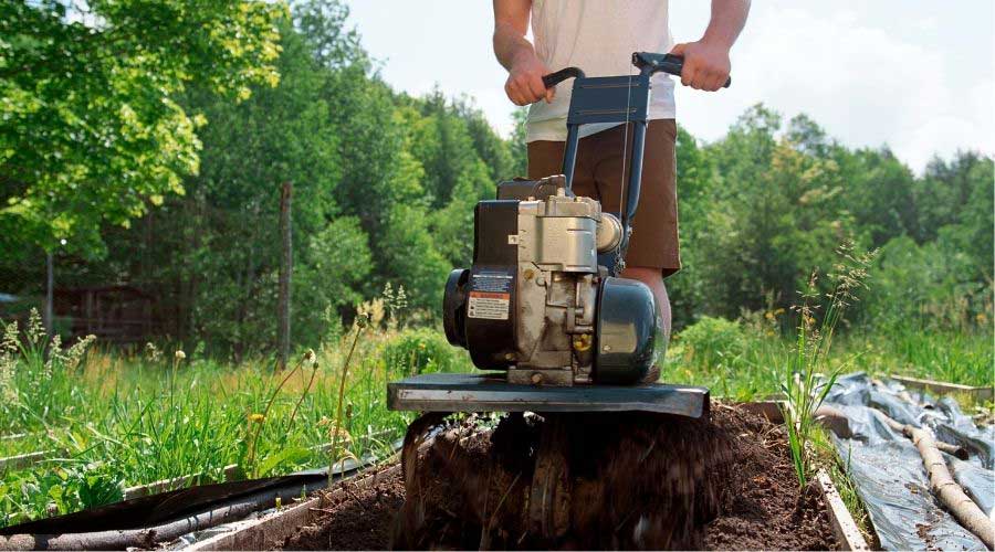 Person tilling the ground with a multi-tilling machine.