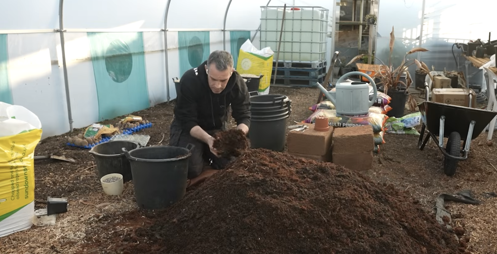 Tony O'Neill mixing homemade compost and coconut coir for container potato growing in his polytunnel at Simplify Gardening